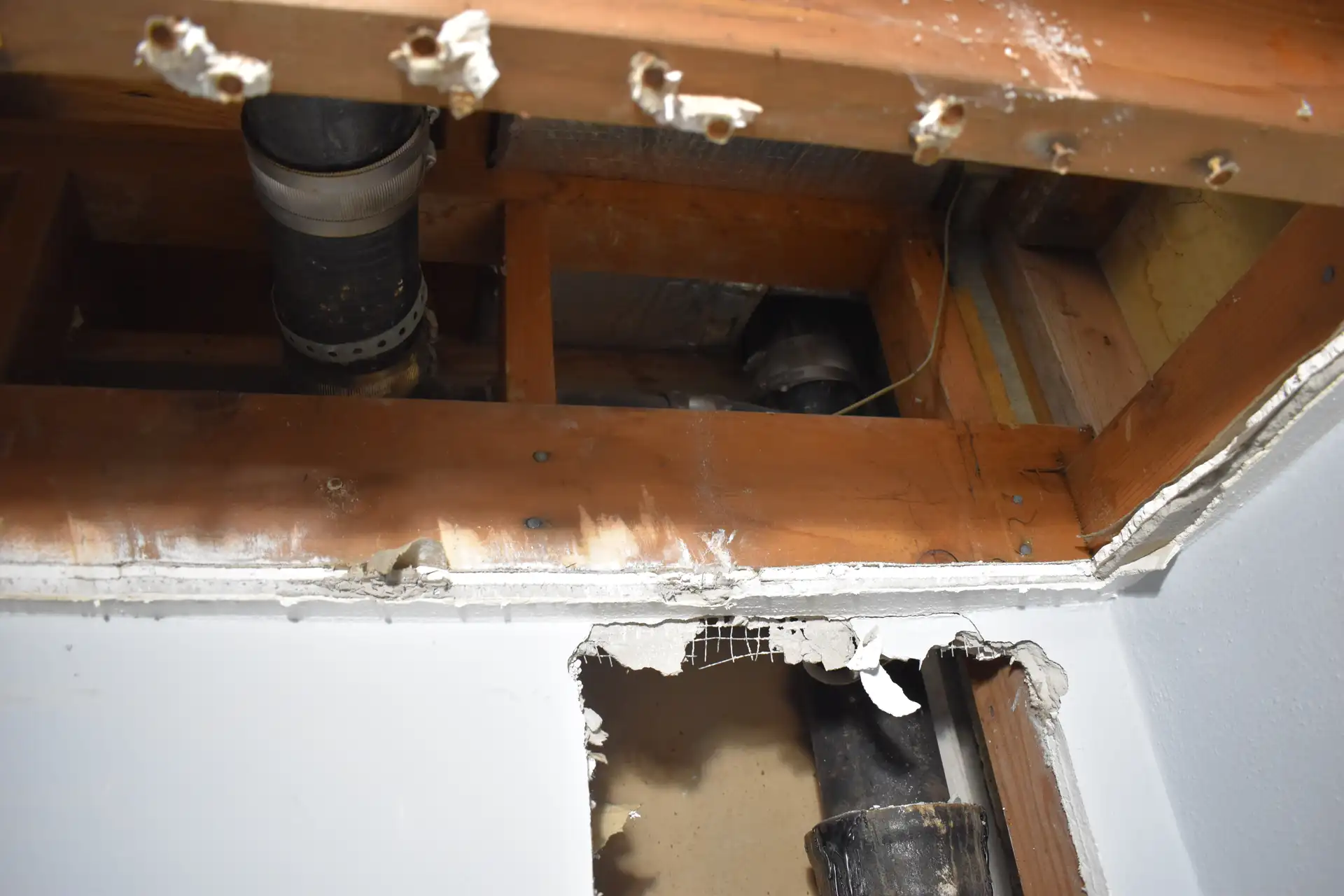 Cast iron pipe exposed behind wall showing corrosion damage in Miami home