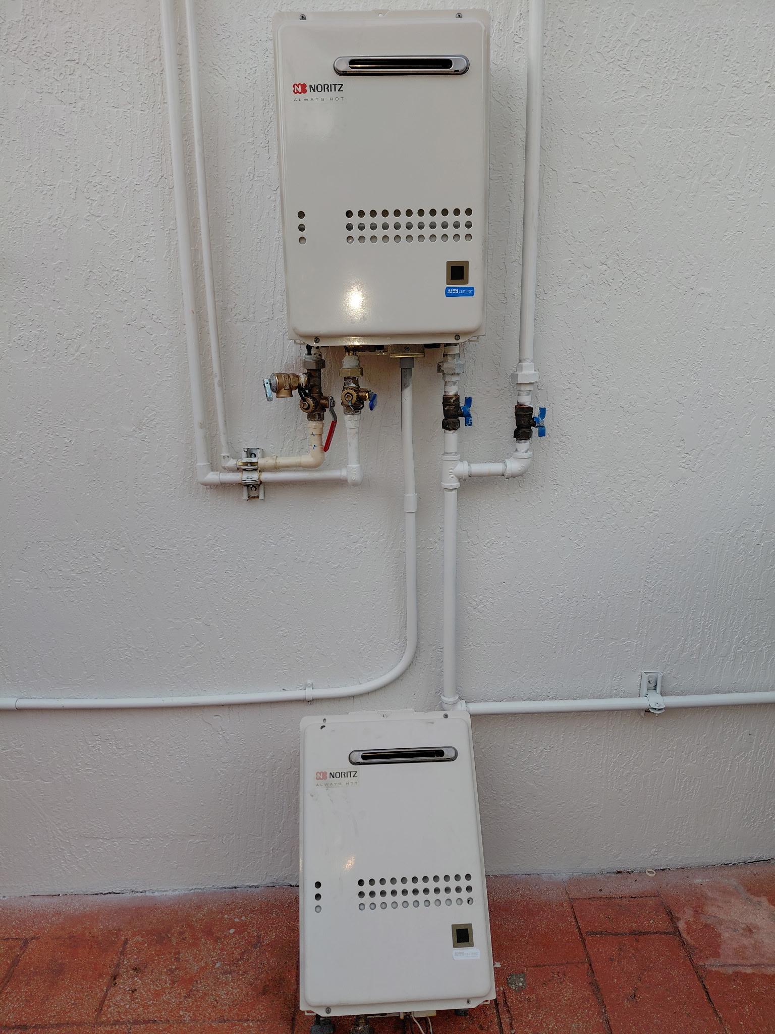 Outdoor gas tankless water heater installation with proper PVC venting and piping connections