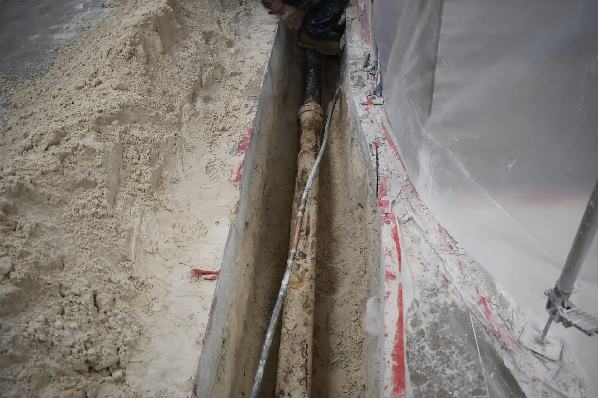Plumber exposing corroded cast iron pipe in trench for replacement - Hernandez Plumbing Miami